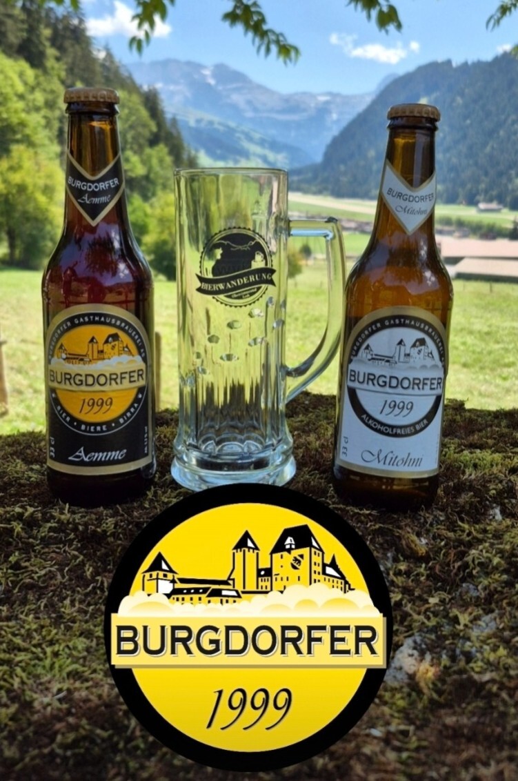 Burgdorfer Bierflaschen und Glas vor alpiner Landschaft, mit Logo im Vordergrund, perfekt für entspannte Bierwanderung.