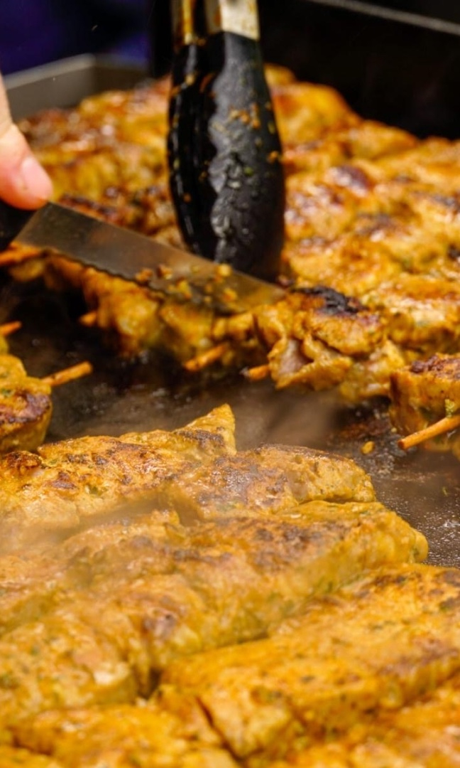 Gegrillte Kebabs auf einer heißen Platte, frisch geschnitten und servierbereit.